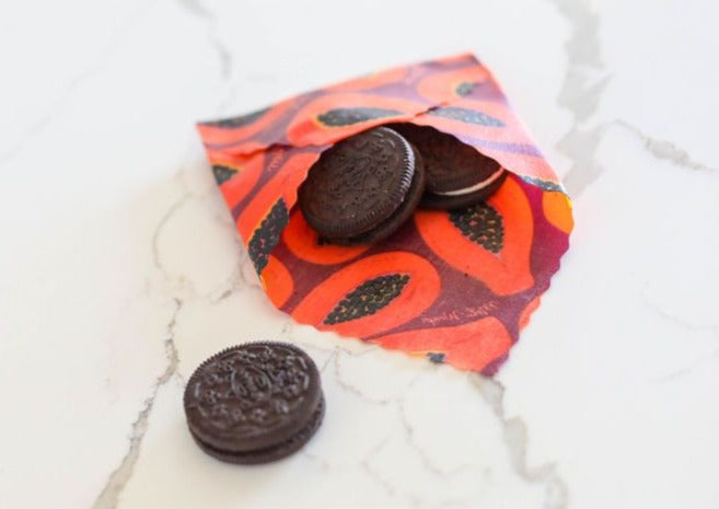 Meli Wraps Beeswax Wraps photo of a bulk roll of beeswax wraps in purple papaya print folded into an envelope to hold oreo cookies.
