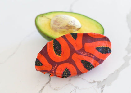 Meli Wraps Beeswax Wraps photo of a bulk roll of beeswax wraps in purple papaya print covering half an avocado.